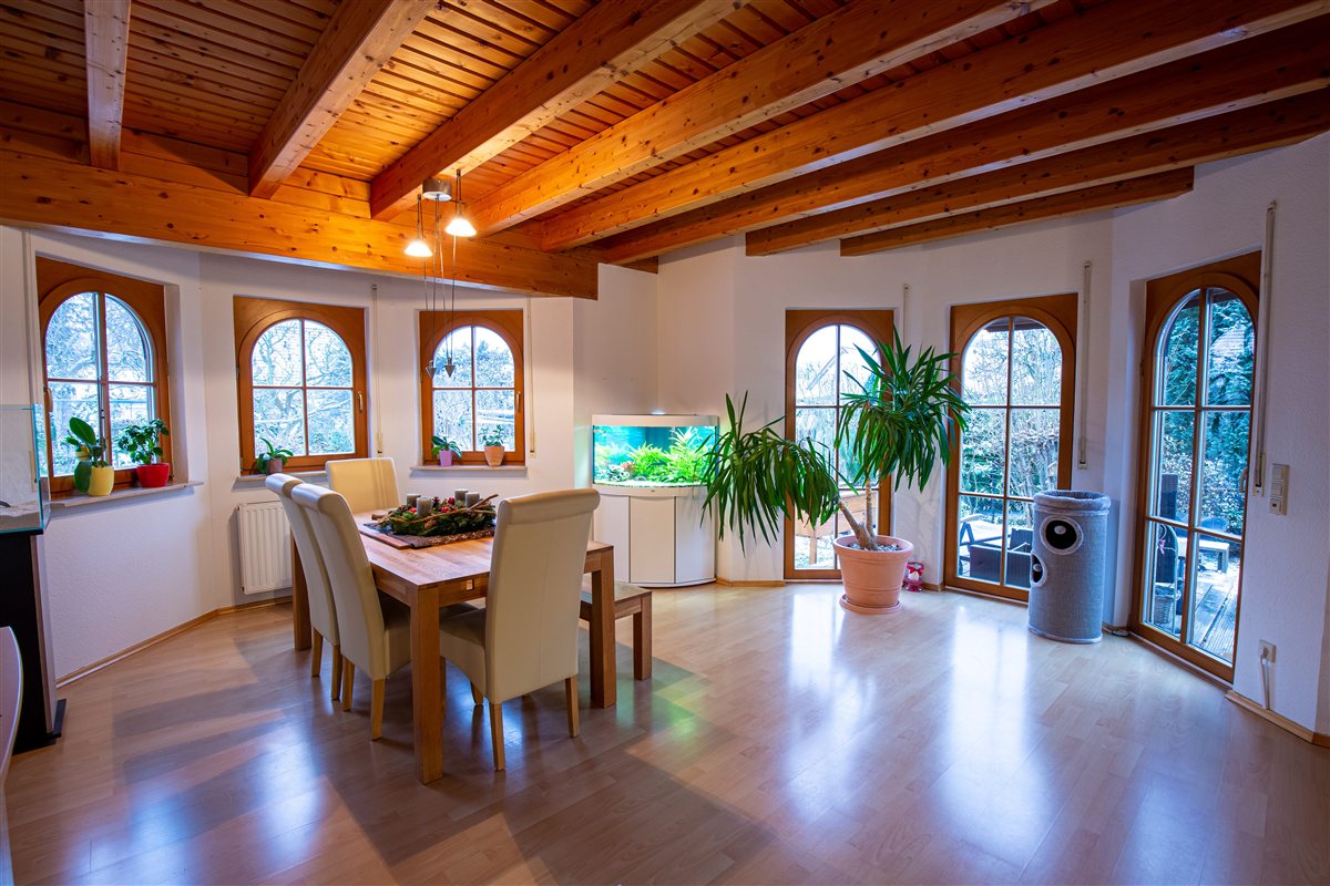 Rustikales Wohnzimmer mit Holzbalkendecke und Bogenfenstern